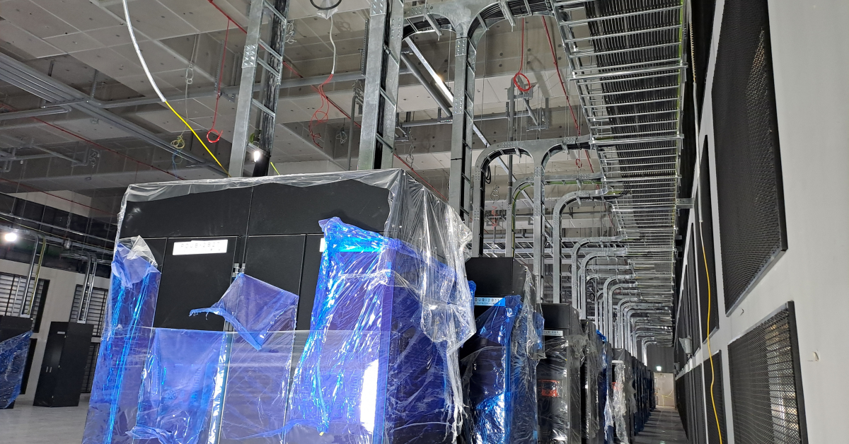 Interior of a data center under construction featuring server racks and overhead cable trays, representing new data center construction and permitting timelines.