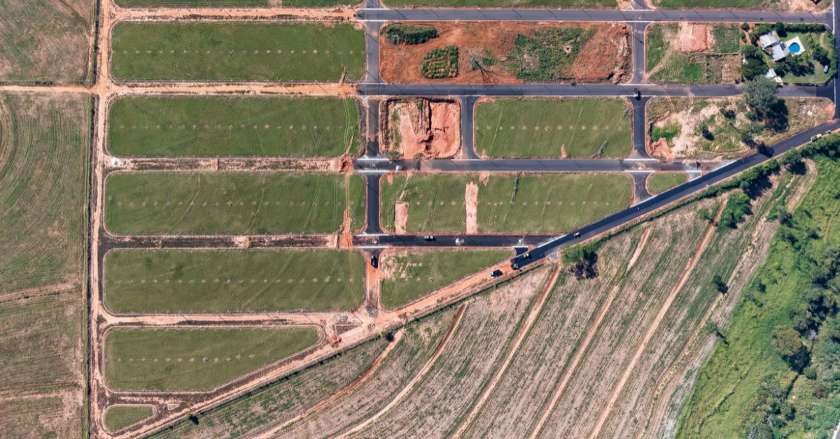High-angle aerial view showing divided land plots, road access, and agricultural boundaries, representing key land investing terms and parcel concepts researched on Acres