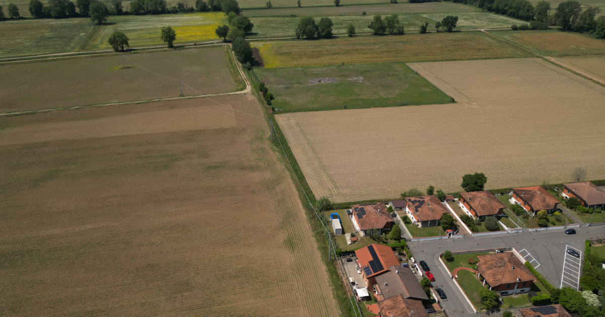 Aerial view of adjacent agricultural land parcels and residential development illustrating how land price per acre varies by property location and use.